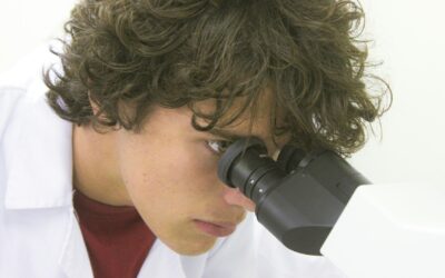 Młoda osoba patrzy przez mikroskop w laboratorium